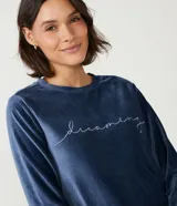 Conjunto de pijama largo de plush azul oscuro, compuesto por una blusa de manga larga con cuello redondo y bordado de lettering en blanco, y un pantalón largo de corte recto.