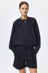 Short negro de tiro alto en mezcla de lino, algodón y viscosa, con pliegues frontales y posteriores, bolsillos al bies y bajos con vuelta cosida.