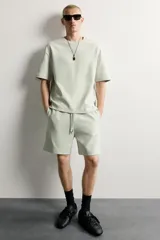 Bermuda estilo jogger de ajuste relajado, confeccionada en tejido interlock de algodón. Cuenta con cintura elástica ajustable con cordón, bolsillos frontales de vivo y diseño liso.