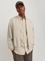 Campera bomber color beige, de manga larga, con cuello baseball y cierre frontal de cremallera.