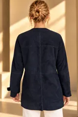 Camisa de cuero color marrón, de corte recto y largo medio, con cuello redondo a la base, cierre frontal con broches metálicos y bolsillos aplicados en los laterales.