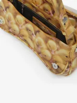 Bolso de mano tipo clutch con forma curva y acabado brillante, estampado con un patrón de patitos amarillos. Posee un cierre frontal metálico con el logo de la marca.