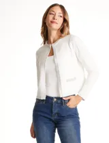 Chaqueta tejida blanca de la marca Rio & Rian, con cuello a la base bordado con perlas y canutillos. Cuenta con broche de enganche interno, bolsillos simulados en la delantera con aplique de brillos, y vivo delantero y puños en tejido lurex.