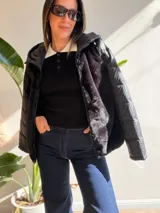 Campera negra con diseño híbrido que combina cuerpo de piel sintética (teddy) y mangas acolchadas con costuras horizontales. Cuenta con capucha, cierre frontal y bolsillos laterales.