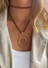 Colgante con dije en forma de espiral de alpaca color bronce, con cadena de cuero marrón.