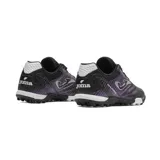 Championes de fútbol Joma Maxima, diseñados para césped artificial. Presentan un diseño de perfil bajo con cordones, fabricados en material sintético de alta calidad con detalles en color violeta y blanco sobre base negra. Cuentan con suela de goma con patrón de agarre optimizado y sistema de ventilación.