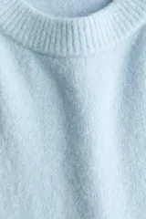 Buzo oversized celeste de punto suave levemente cepillado, con cuello redondo, hombros caídos y ribetes acanalados en puños y bajo.