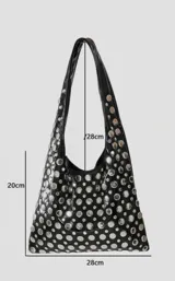 Cartera negra tipo tote bag con tachas circulares plateadas.