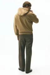 Campera con capucha de corte boxy confeccionada en felpa de algodón pesado. Presenta cierre frontal completo, bolsillos tipo canguro, capucha forrada y terminaciones acanaladas en puños y ruedo.