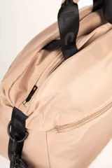 Bolso de mano color rosa con correa de hombro negra con letras blancas.