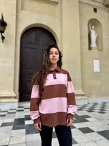 Buzo deportivo de corte holgado con diseño de rayas horizontales anchas en color marrón y rosado. Presenta cuello tipo polo con cierre frontal de botones y mangas largas con puños ajustados.
