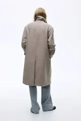 Abrigo cruzado de lana hasta la rodilla, con solapas de muesca, cierre de doble botonadura frontal y bolsillos insertados. Presenta trabillas con botón en los puños y abertura posterior, completamente forrado.