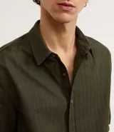 Camisa de manga larga color verde militar, confeccionada en algodón con textura maquinetada, cuello inglés y abotonado delantero. Corte comfort.