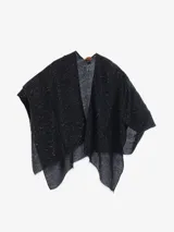 Capa tipo bufanda de tacto suave, con diseño en zigzag en tonos oscuros y detalles brillantes o lentejuelas. Presenta un escote en V cruzado y bordes deshilachados.