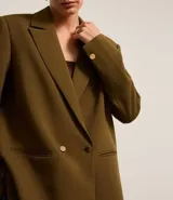 Blazer oversize color verde oliva, con solapas en el cuello y doble abotonadura delantera.