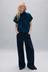 Jersey de punto de textura suave en color azul, con cuello redondo ajustable mediante cordones del mismo tejido y manga corta.
