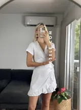 Vestido corto rojo con escote cruzado, mangas cortas y falda con volados. Se ajusta con lazo lateral tipo pareo.