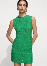 Vestido corto de crochet en color verde vibrante, con diseño recto, cuello redondo y sin mangas. Presenta un tejido de punto grueso con patrón calado y terminaciones festoneadas en el ruedo.
