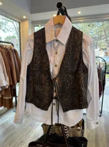 Chaleco de jean con estampado animal print de serpiente en tonos marrones y negros, escote en V y cierre frontal con tiras para atar.