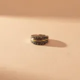 Anillo de plata con banda central de oro y dos filas de circonias engastadas en los bordes con acabado envejecido.