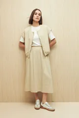 Chaleco color beige sin mangas de silueta relajada, con escote redondeado, cierre frontal con cremallera y ruedo elastizado.