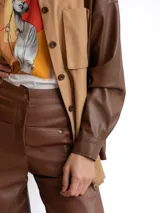 Pantalón de corte recto y tiro alto confeccionado en cuero sintético color marrón, con bolsillos laterales y cierre frontal.
