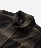 Camisa de franela a cuadros en tonos de azul marino y gris oscuro, con corte regular, manga larga, cuello camisero, cierre frontal de botones y un bolsillo en el pecho.