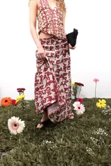 Falda larga de gasa con estampado tipográfico en color bordó sobre fondo beige. Presenta una silueta fluida y cierre lateral oculto.