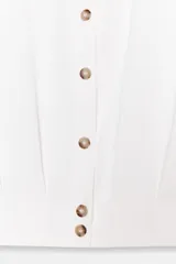 Camisa corta de cuello solapa y manga larga, con trabillas decorativas en los hombros. Presenta pliegues delanteros, elástico en la espalda y cierre frontal con botones.