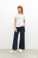 Remera blanca de manga corta con cuello en V, adornada con un bordado floral en color verde menta en el área del pecho y ribetes del mismo color en el cuello y mangas.