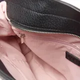 Cartera grande de símil cuero color negro, tipo tote bag, con doble asa de mano y correa larga de tela ajustable. Cuenta con detalles de cordones con nudos en los laterales y el logo metálico de la marca en la parte frontal.