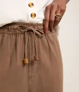 Pantalón marrón de cintura alta y corte recto cropped, confeccionado en sarga de viscosa. Cuenta con cintura elástica ajustable con lazo, bolsillos delanteros y diseño liso.