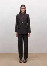 Blazer de corte sastre y diseño cruzado, con cierre de botones frontales, solapas clásicas y bolsillos laterales con solapa. Presenta una estructura entallada y hombros definidos.
