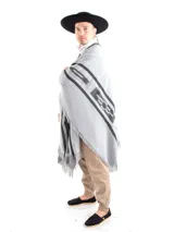 Poncho de tejido de punto en color gris con detalles geométricos en negro y terminaciones con flecos.