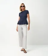 Blusa de corte peplum confeccionada en tejido Punto Roma, con escote redondo, mangas cortas y recortes estructurados que definen la silueta.