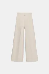 Jeans de tiro alto confeccionados en mezcla de algodón, con diseño de pierna ancha y costura marcada en el delantero. Presenta cintura con trabillas, cierre frontal con cremallera, botón y gancho metálico, y bolsillos de plastrón en la espalda.