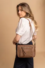 Bandolera de tamaño mediano confeccionada en símil cuero con detalles en nobuck. Presenta un diseño rectangular con cierre principal, bolsillos frontales con cierre y correa larga ajustable para llevar al hombro o cruzada.