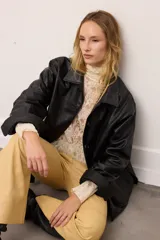 Chaquetón de cuero negro oversized, con corte recto y bolsillos delanteros. Presenta un bordado en los bolsillos inspirado en la costa atlántica.