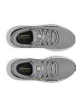 Championes de running Under Armour Charged Surge 4, color gris con detalles en verde lima y blanco. Presentan una parte superior de malla transpirable con refuerzos sintéticos, entresuela Charged Cushioning para mayor amortiguación y suela de goma resistente.