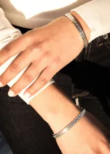 Pulsera esclava abierta de acero quirúrgico plateado con diseño labrado.