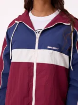 Campera rompevientos Rusty con diseño color block en tonos bordó, azul y blanco. Cuenta con cierre frontal, capucha con cordones ajustables, puños elásticos y logo bordado en el pecho.