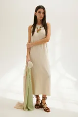 Vestido midi de tejido de punto en color beige, con cuello redondo y diseño sin mangas. Presenta un corte recto y holgado con una caída fluida.