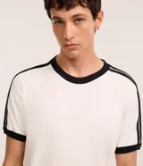 Remera de algodón color celeste con cuello redondo y bordes de mangas en color blanco. Presenta diseño de rayas dobles blancas en los hombros y mangas.
