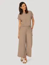 Conjunto de dos piezas compuesto por una remera de manga corta con cuello redondo y frunces laterales ajustables, y un pantalón de corte ancho con cintura elástica y bolsillos laterales.