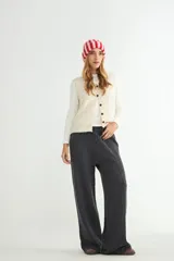Pantalón de punto color crema, de corte recto y holgado, con cintura elástica y cordón ajustable. Presenta costuras verticales decorativas a lo largo de las piernas.