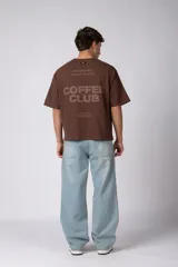 Remera boxy de algodón color marrón, de mangas corta y calce holgado, con estampa sutil con la leyenda 'COFFEE' en el pecho.