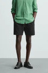 Bermuda de algodón color beige claro, de corte regular fit, con cintura elástica ajustable mediante cordón. Presenta bolsillos laterales y un bolsillo trasero de vivo.