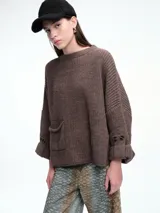 Sweater de tejido de punto color marrón con textura tipo waffle, diseño amplio, hombros caídos y cuello redondo. Presenta un bolsillo frontal aplicado y mangas con puños anchos decorados con botones.