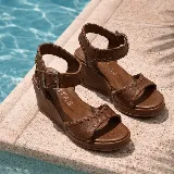 Sandalias de plataforma tipo cuña, color marrón, con tiras de cuero texturizado y costuras decorativas. Cuentan con tira al tobillo con hebilla metálica y plataforma corrida.