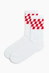 Medias blancas de caña alta con diseño de damero o ajedrez rojo en la parte superior.